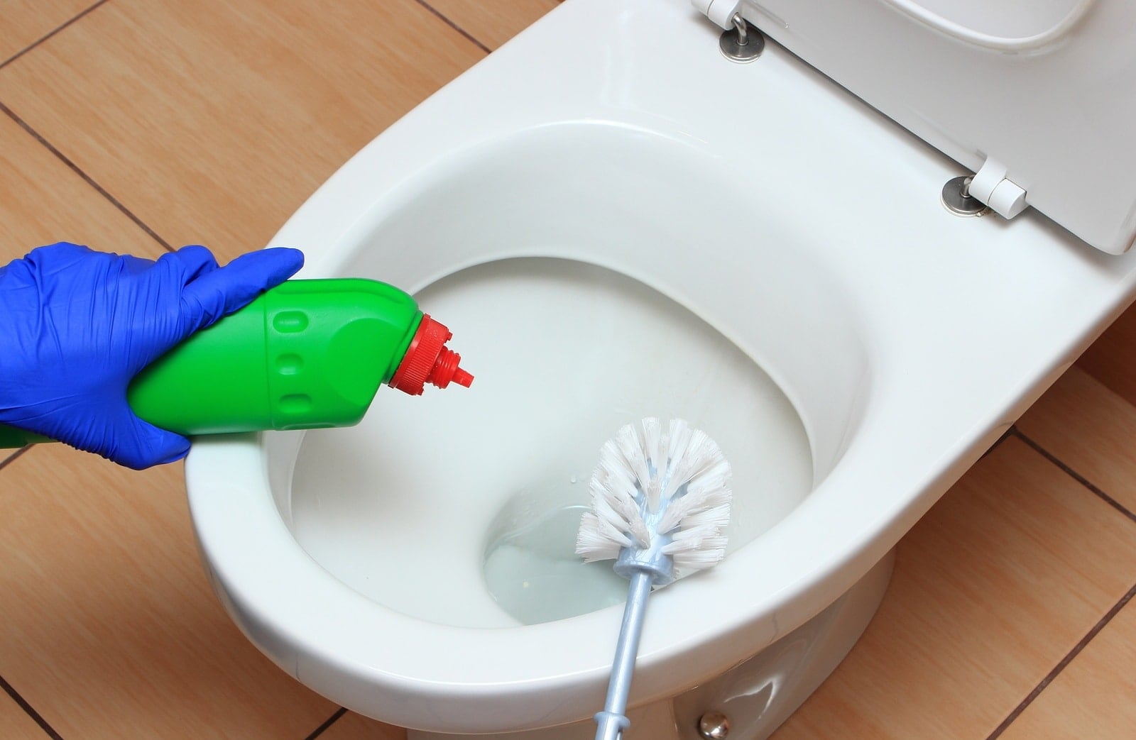 Ruční čištění toalety s pomocí čisticího prostředku a WC kartáče – klasická metoda boje s vodním kamenem.