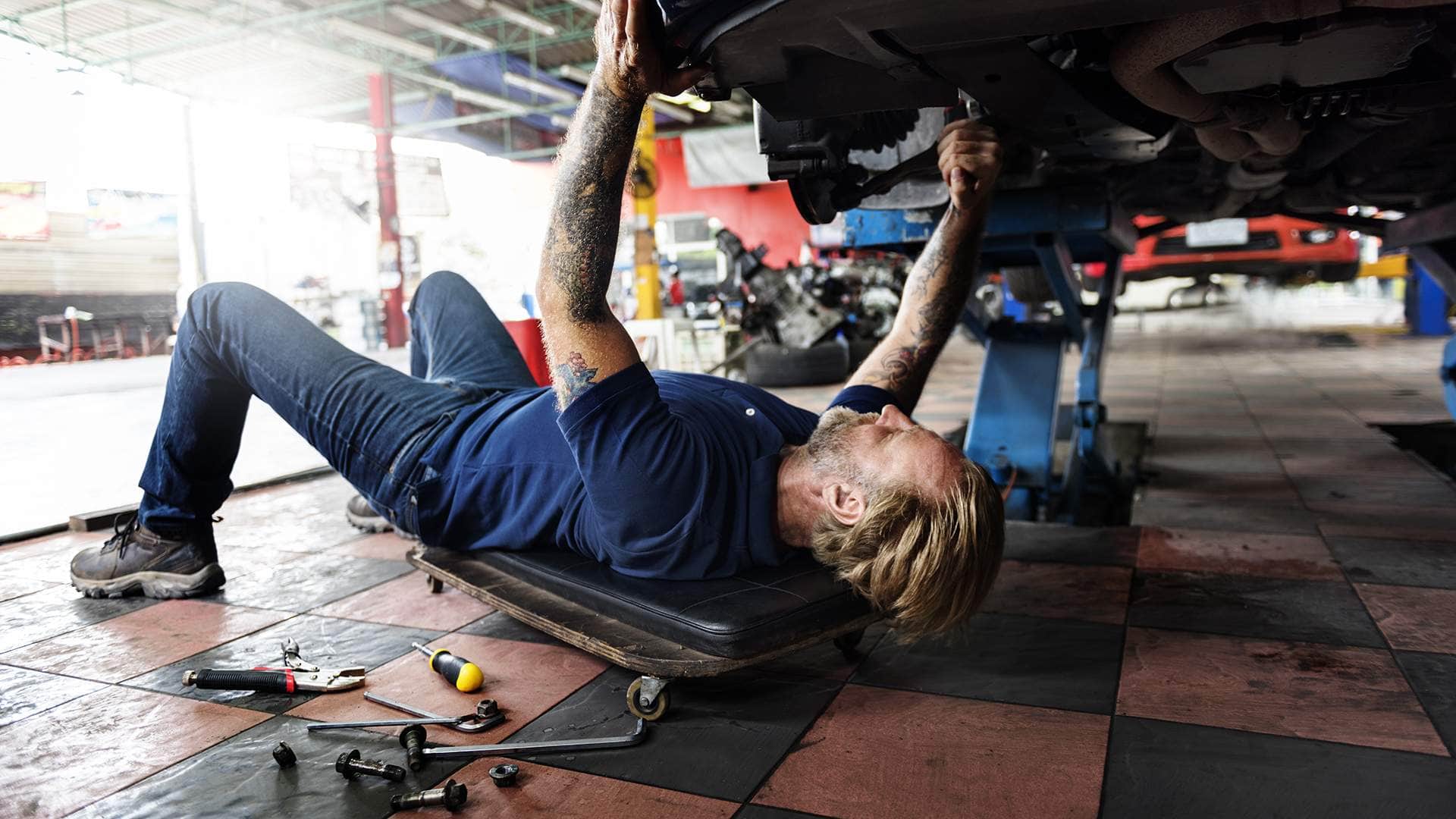 Automechanik opravuje podvozek auta v autoservisu – údržba spolehlivých automobilů a kontrola technického stavu
