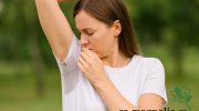 Žena venku zkoumá mokré podpaží se skvrnou na tričku – přírodní deodorant na podpaží jako řešení proti potu a zápachu bez chemie.